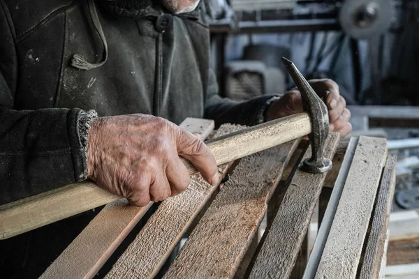 Primer plano del maestro carpintero trabajando en su carpintería o taller. Martillo en la mano vieja —  Fotos de Stock