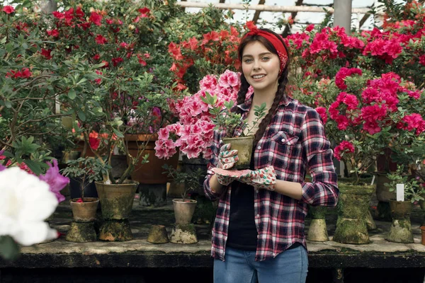 Joven jardinero deportivo hermoso con leer diadema sosteniendo plantas en la mano — Foto de Stock
