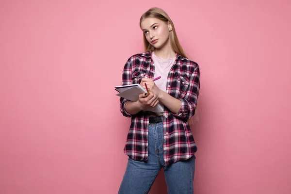 Upprörd vacker blond flicka student i casual kläder stående mot rosa vägg — Stockfoto