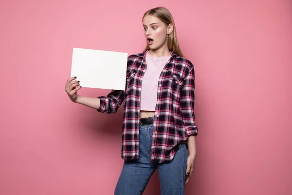 Choqué jeune femme bouleversée en vêtements décontractés, tenant blanc vide pour votre texte — Photo