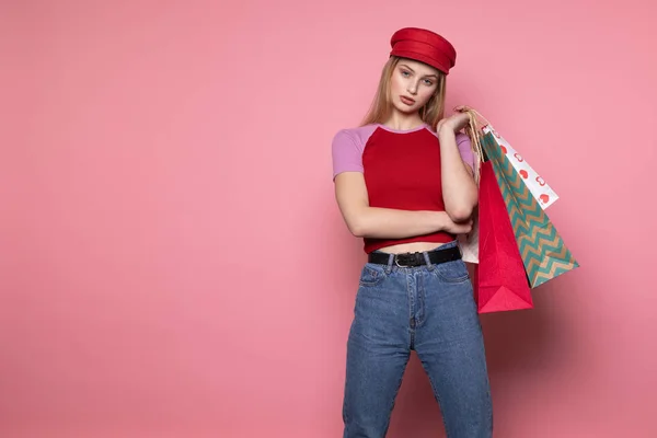 Assez sérieusement jeune modèle féminin en chapeau rouge élégant debout contre le mur rose — Photo