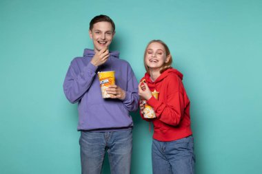 Mavi arka planda soyutlanmış, gündelik giysiler içinde genç mutlu bir çift.