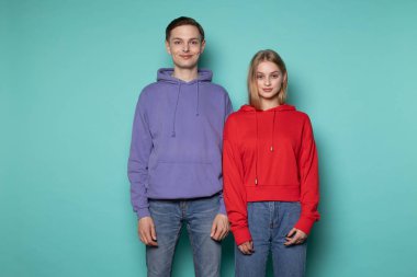 Mavi duvara karşı yan yana duran sıradan elbiseli güzel bir çift.