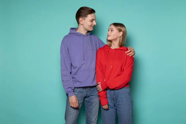 Młoda piękna para w luźnych ubraniach stojąca razem pod niebieską ścianą — Zdjęcie stockowe
