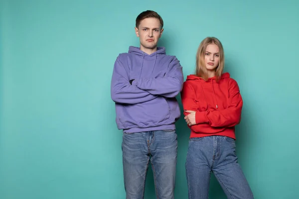 Malheureux gens en colère homme et femme en vêtements décontractés, debout ensemble contre le mur bleu dans le studio — Photo