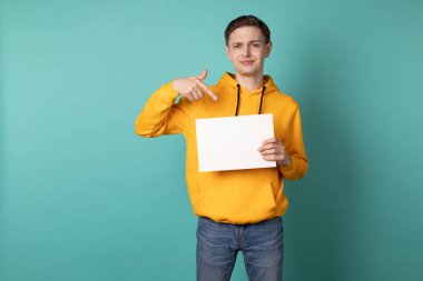 Sarı kapüşonlu ciddi eoropean adam beyaz boş işaret ediyor