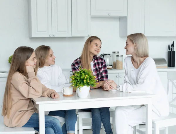 Lycklig lesbisk familj sitter tillsammans i köket hemma, alla i casual kläder — Stockfoto