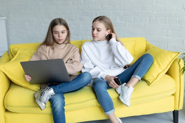 Två unga attraktiva affärskvinna i casual kläder sitter tillsammans på gul soffa — Stockfoto