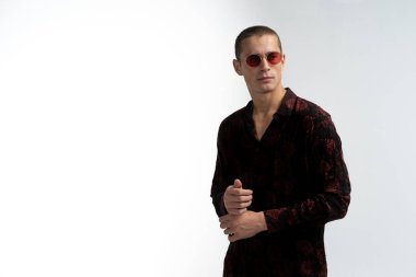 Kısa saçlı, kırmızı güneş gözlüğü takan, gömlekleri düzelten, kısa saçlı, çekici bir adam.