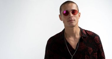 Kırmızı güneş gözlüğü kısa saç kesimi ile Mutlu genç çekici adam, trendy siyah gömlek giyen, kameraya bakarak, beyaz arka plan üzerinde izole