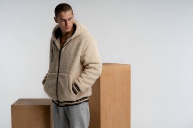 Kısa saç kesimi ile Ciddi yakışıklı adam, şık spor giyim giyiyor, sağa bakıyor, ceplerinde el ele tutuşarak, beyaz arka plan üzerinde izole