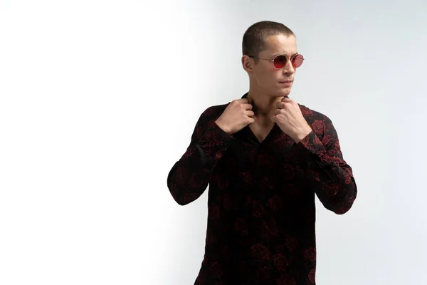 Mladý atraktivní muž s krátkým účesem, s červenými slunečními brýlemi, narovnává límec košile, kopíruje prostor pro text — Stock fotografie