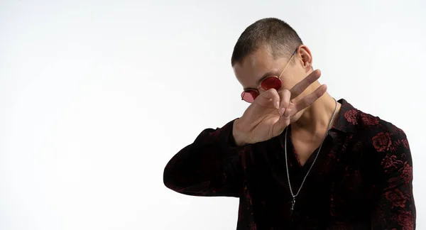 De cerca foto de hombre serio alegre y seguro que muestra signo de paz, con camisa negra y gafas de sol rojas aisladas sobre fondo blanco — Foto de Stock