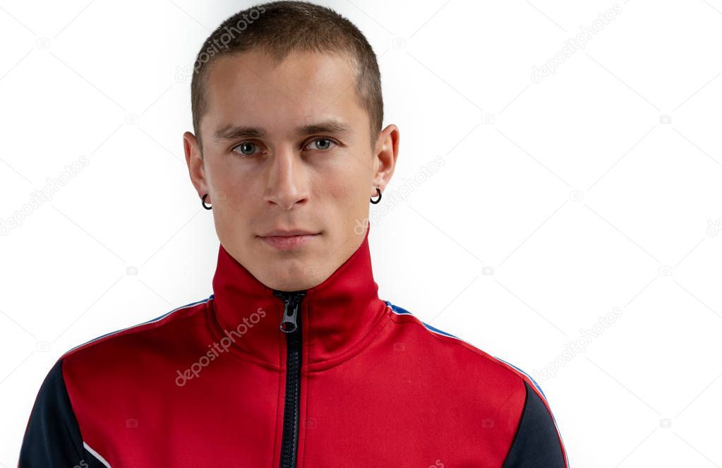 Closeup photo of casually dressed young man standing isolated on white background, looking seriously at the camera