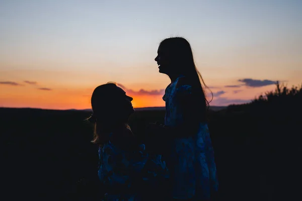 Силует щасливої мами і дочки на фоні заходу сонця — стокове фото