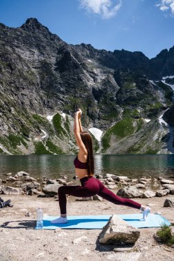 Kırmızı spor genç güzel kız dağ gölü yakınında yoga uygulaması yapıyor, sağlıklı yaşam kavramı ve vücut ve zihinsel gelişim arasında doğal denge