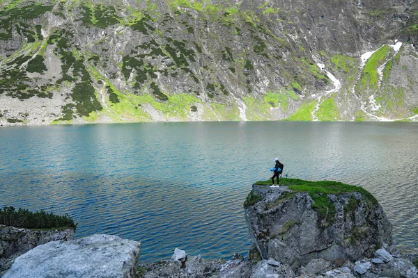 Güzel göl, aktif yaşam tarzı kavramı yakınında büyük kaya dağ üzerinde duran kız gezgin