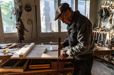 Gri giysiler kıdemli marangoz ev atölyesinde ahşap iş yapma, iş odaklı