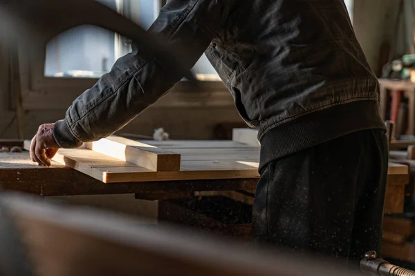 Photo recadrée d'un vieux maître charpentier en vêtements gris tenant des planches en bois à la main — Photo