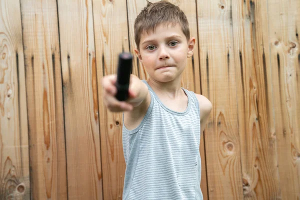 Poloviční délka malého chlapce v šedivém triku, který hraje s černou trubkou izolovanou na pozadí dřevěné zdi — Stock fotografie