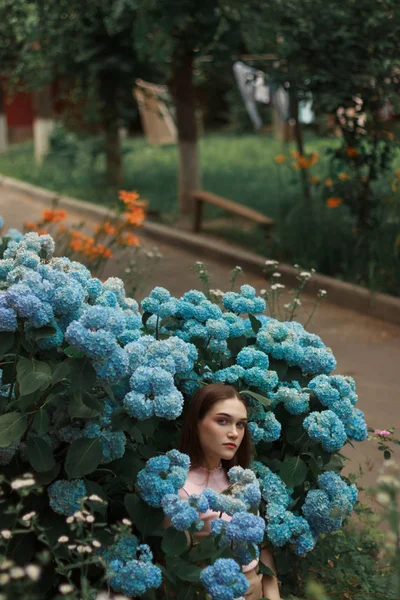 Wesoła młoda kobieta z brunetką włosy stojące wśród niebieskich kwiatów — Zdjęcie stockowe