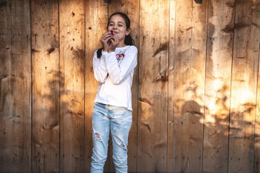 Ahşap arka plan üzerinde izole yüz yakın ellerde ahududu tutan rahat giysiler içinde Mutlu gülümseyen esmer kız