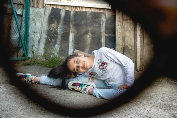 Foto al aire libre a través de las gafas de hermosa morena niña en ropa casual sentado en el suelo y estiramiento — Foto de Stock