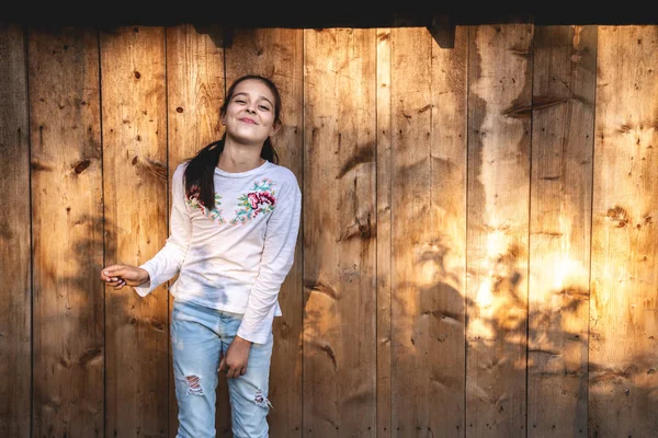 Ευτυχισμένο χαμογελαστή μικρή μελαχρινή κορίτσι με λευκό μπλουζάκι και μπλε τζιν απομονώνεται πάνω από ξύλινο φόντο — Φωτογραφία Αρχείου