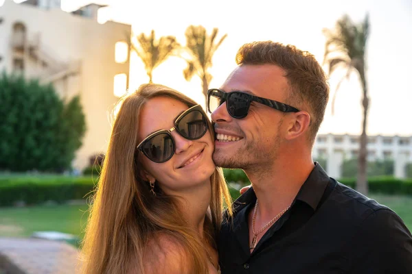 Close up portrait of beautiful smiling boy and girl in sunglasses, sunset on the background — Stock Photo, Image