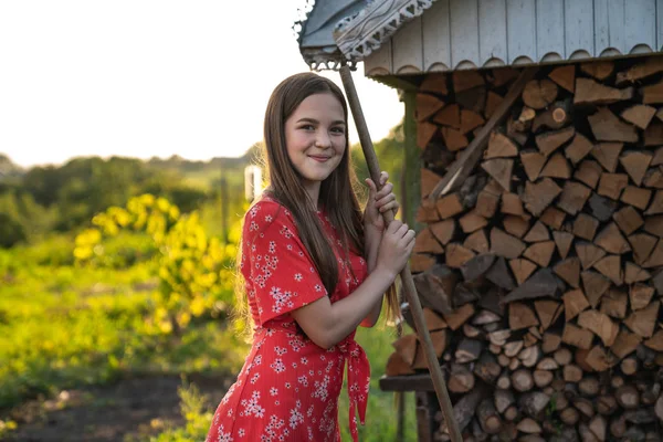 Heureuse fille souriante aux cheveux roux et aux taches de rousseur debout avec des râteaux, des personnes et un concept de jardin — Photo