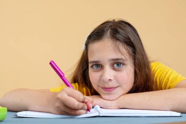 Genç kız tek başına ders çalışıyor ders kitabı okuyor evde oturuyor. Ergenlik çağındaki ergen liseli öğrenci mesafesini kitapla öğreniyor, notlar alıyor.