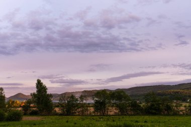 Bulutlu gökyüzünde rengarenk gün batımıyla inanılmaz bir dağ manzarası, doğal seyahat arka planı.