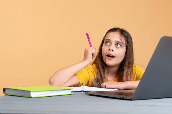 Brünette Teenager-Mädchen mit Stift in der Hand mit Online-Schulklasse zu Hause lizenzfreie Stockfotos
