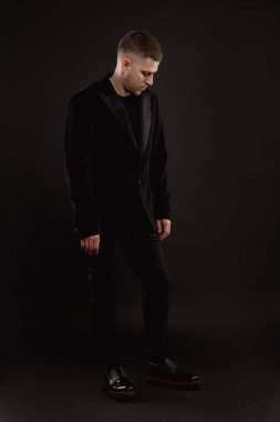 Resmi takım elbiseli yakışıklı adam siyah arka planda izole edilmiş.