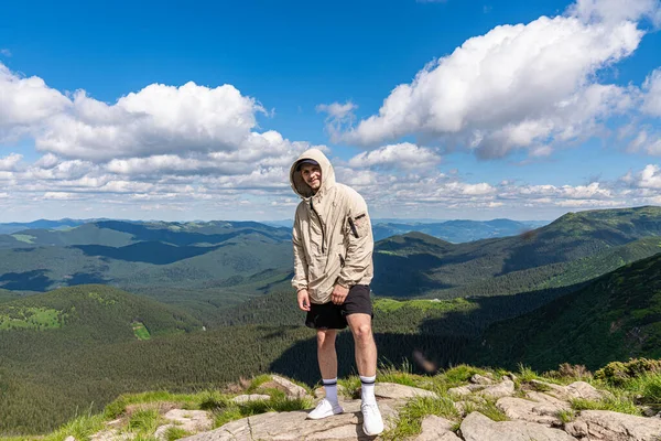 Dağın tepesinde dikilen turist, güzel manzaranın üzerinde gülümsüyor. — Stok fotoğraf