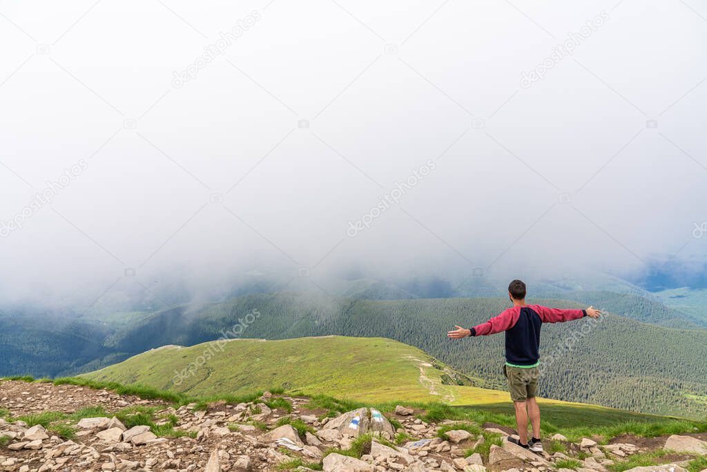 Success, life goals, fitness and achievement concept. Man standing on edge of mountain feeling victorious with arms up in the air