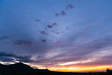 Tepelerin ve tarlaların yukarısındaki kırsal alanda manzara dolu muhteşem bir günbatımı