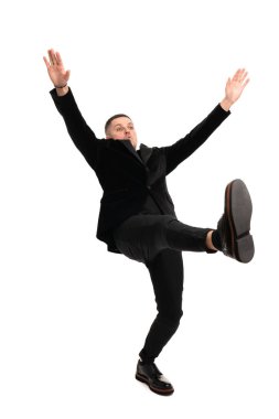 Siyah takım elbiseli, beyaz arka planda tek başına yürüyen yakışıklı bir adamın tam boy çekimi.