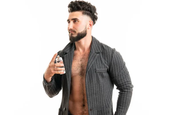 Zakenman die parfum op witte achtergrond aanbrengt. Mannelijke parfum, man met baard in pak. — Stockfoto