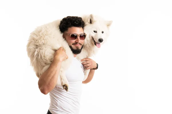 Stylish bearded man in glasses holds samoyed dog on his back, smiling and looking at the camera — Stock Photo, Image