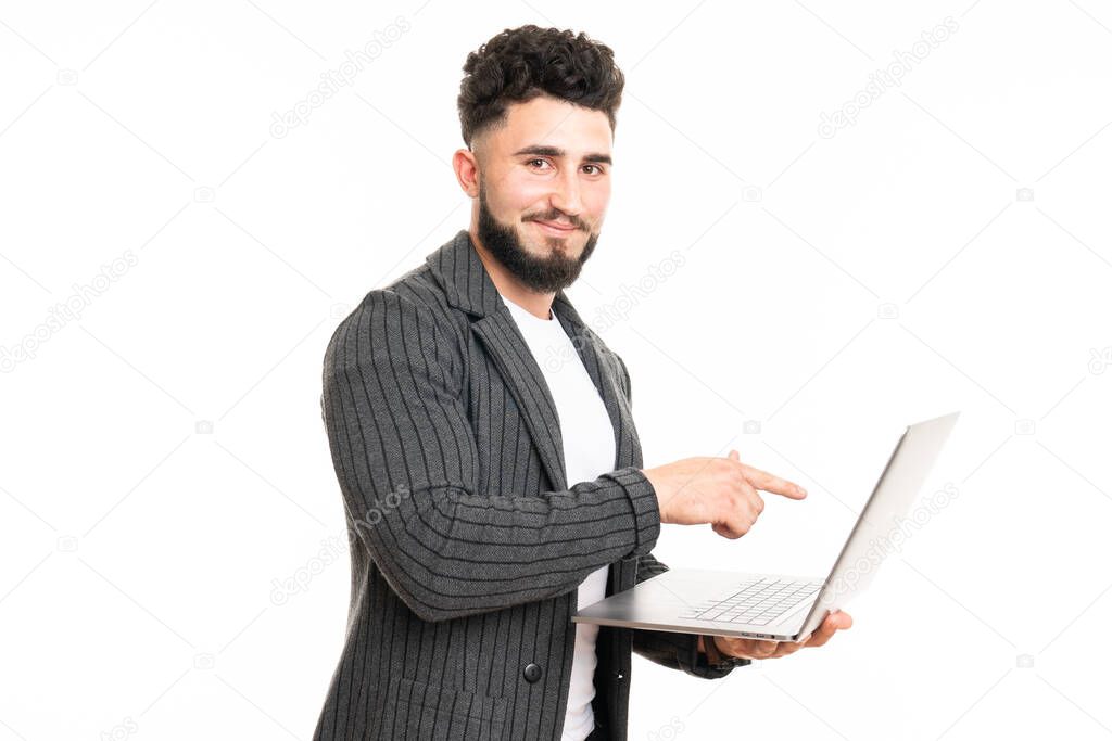 Working with joy. Handsome young man using his laptop and looking at camera with smile while standing against white background