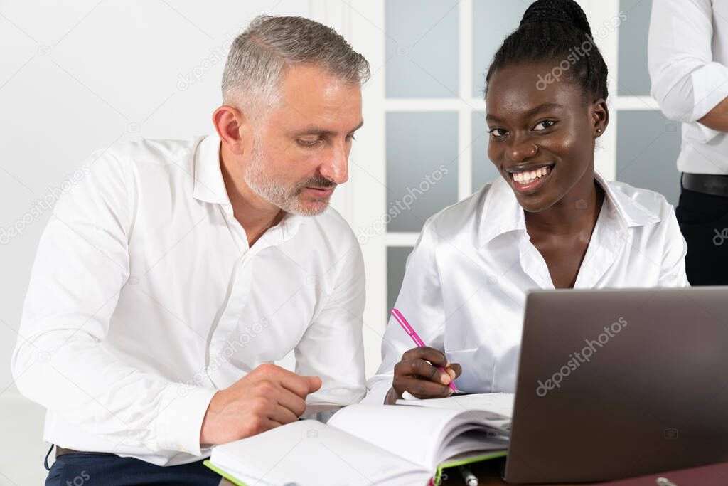 African American businesswoman consulting client about loan or insurance in boardroom, diverse colleagues working on online project together, discussing strategy