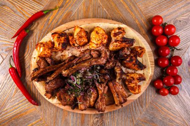 Juicy barbeque pork ribs and dry chicken wings with glaze, beer snacks lie on a wooden tray.