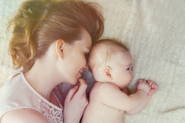 Anne ve çocuğu yatakta yatan. Güneş ışığı