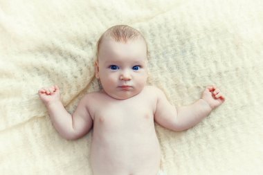 Küçük bir çocuk beyaz bir arka plan üzerinde yatıyor.