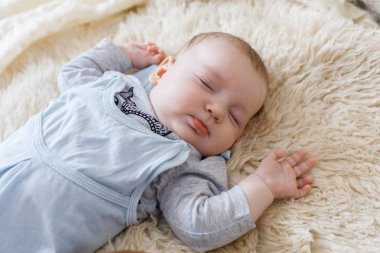 Parlak bir odada uyurken bir yatakta uzanan huzur dolu bir bebek.