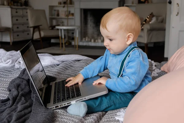 Mały Chłopiec Siedzi Duże Łóżko Ciekawie Wygląda Książka Laptop — Zdjęcie stockowe