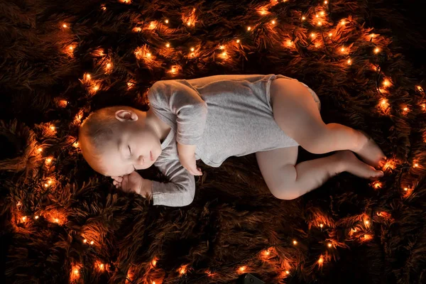 ふわふわの茶色の毛布の上で眠る赤ちゃん ライトは彼のまわりに広がっています — ストック写真