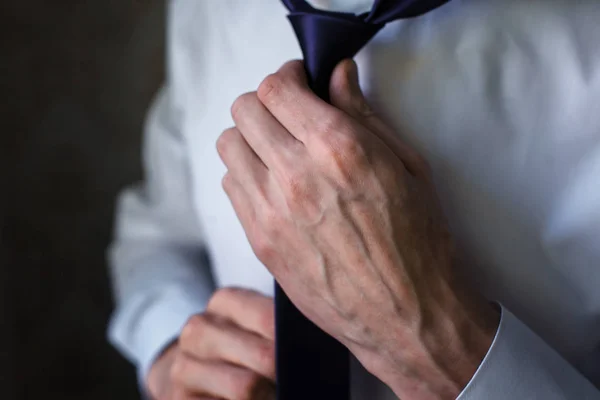 Man in a shirt straightens his tie.