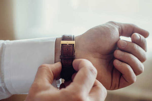 A man fastens a wrist watch on his hand close-up.